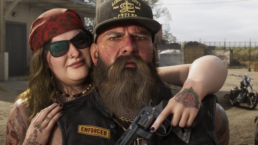 A heavily bearded biker in a leather cut with a name patch poses with a woman in sunglasses and a leather vest in Ambrosia